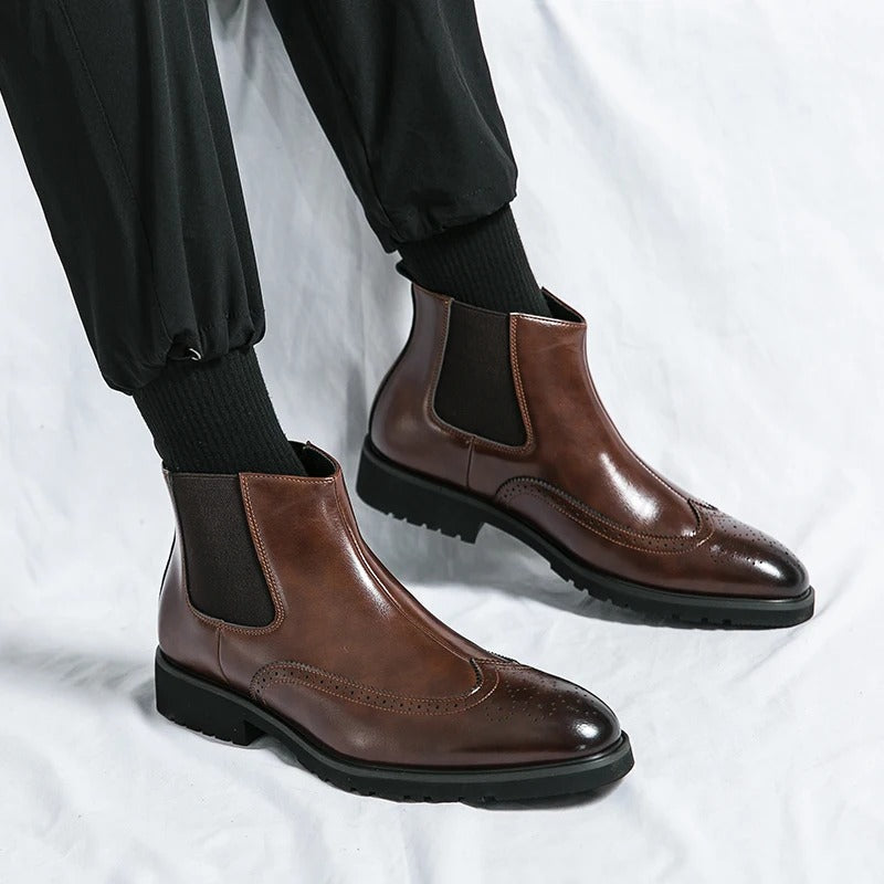 Front view of stylish men's chelsea boots, showcasing the elegant brogue on the toe cap.