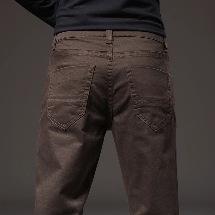 Man sitting comfortably in versatile men's cotton chino trousers. Ideal for relaxed casual wear & movement.