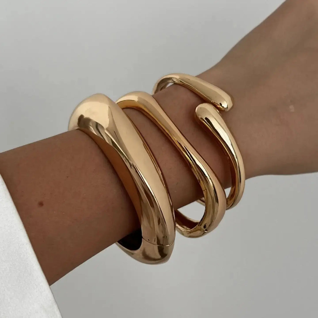 Stackable women's bracelets in gold and silver, showcasing a vintage and sculptural design for a versatile fashion set.