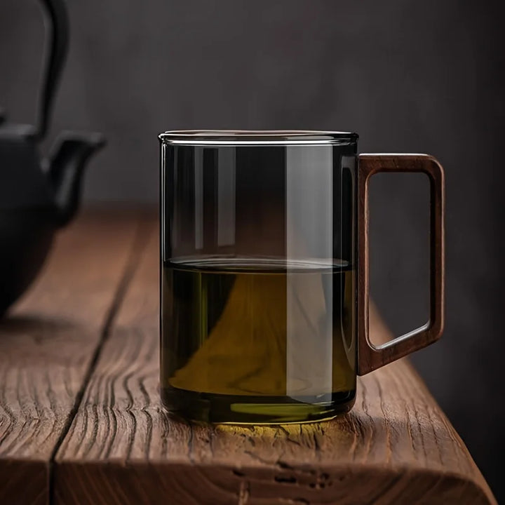 Smoke gray glass coffee mug featuring a stylish walnut handle. Perfect borosilicate drinkware for tea.