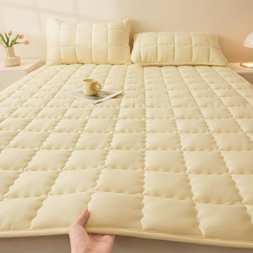 Side angle of the all-season quilted mattress topper, showing its depth and secure fit on a bed