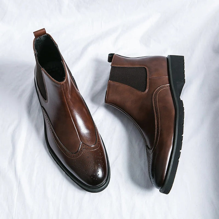 Elegant men's black chelsea boots, brogue details enhance their formal footwear appeal.