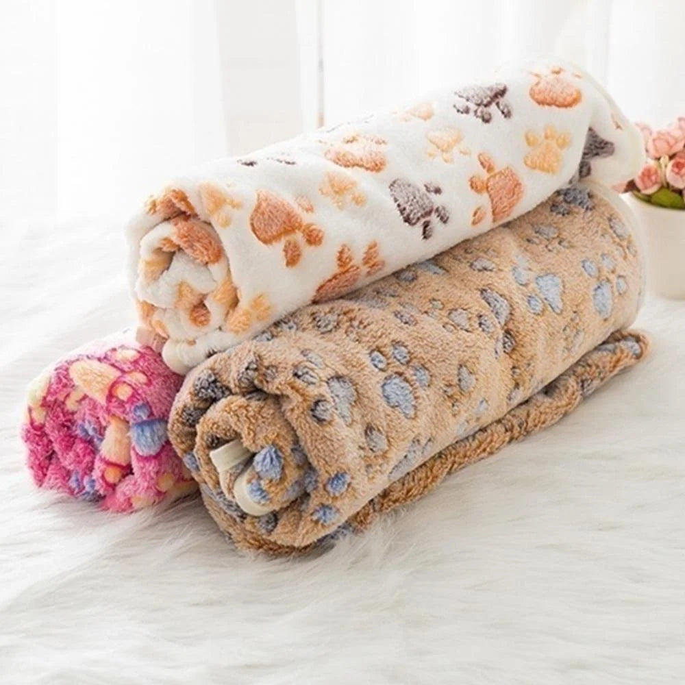 Coral fleece pet blanket draped over a dog bed, showing its use as a soft pet accessory for cats and dogs.