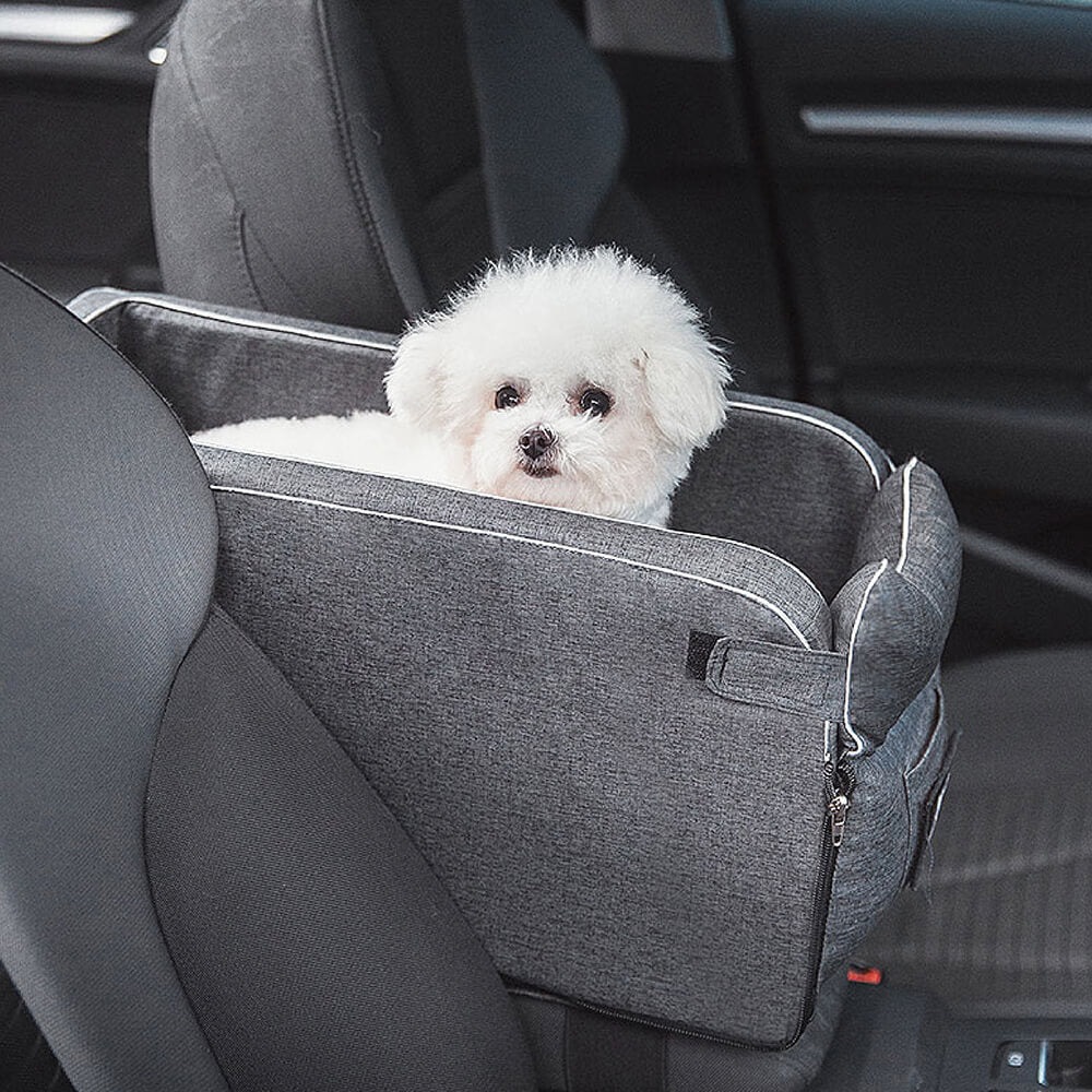 Small dog in a grey suede console car seat, elevated view for anxious pets