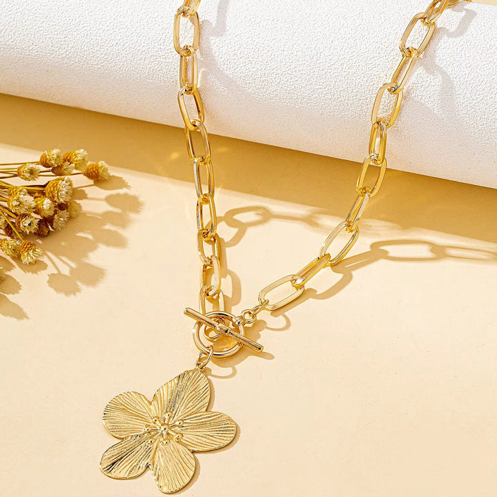 Elegant women's statement wisteria flower pendant necklace. Gold-toned textured floral charm with chunky chain detail.