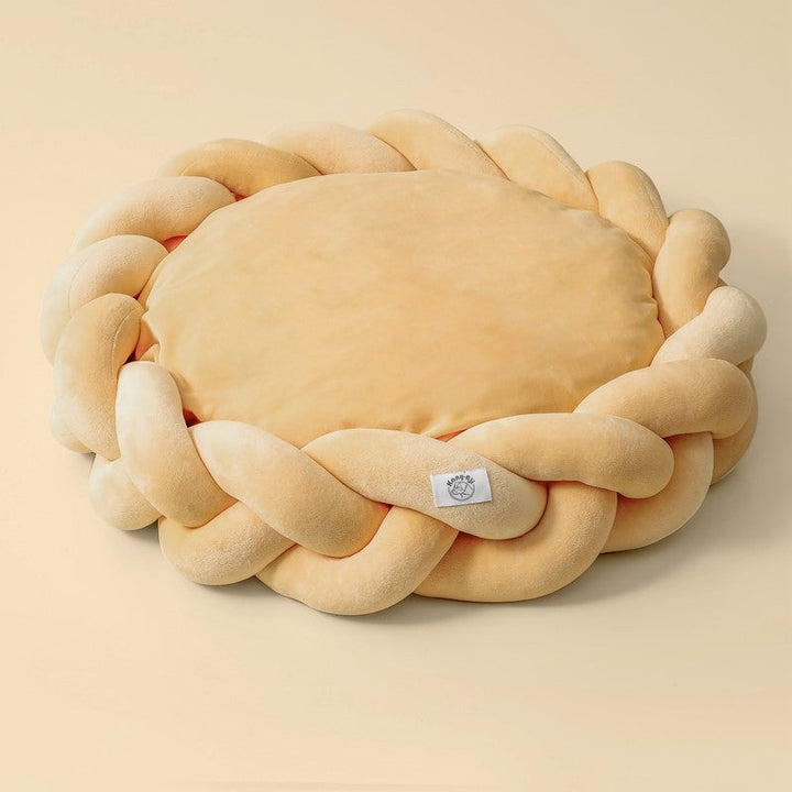 Elegant gray plush dog bed with braided edges, a luxurious addition to pet furniture.