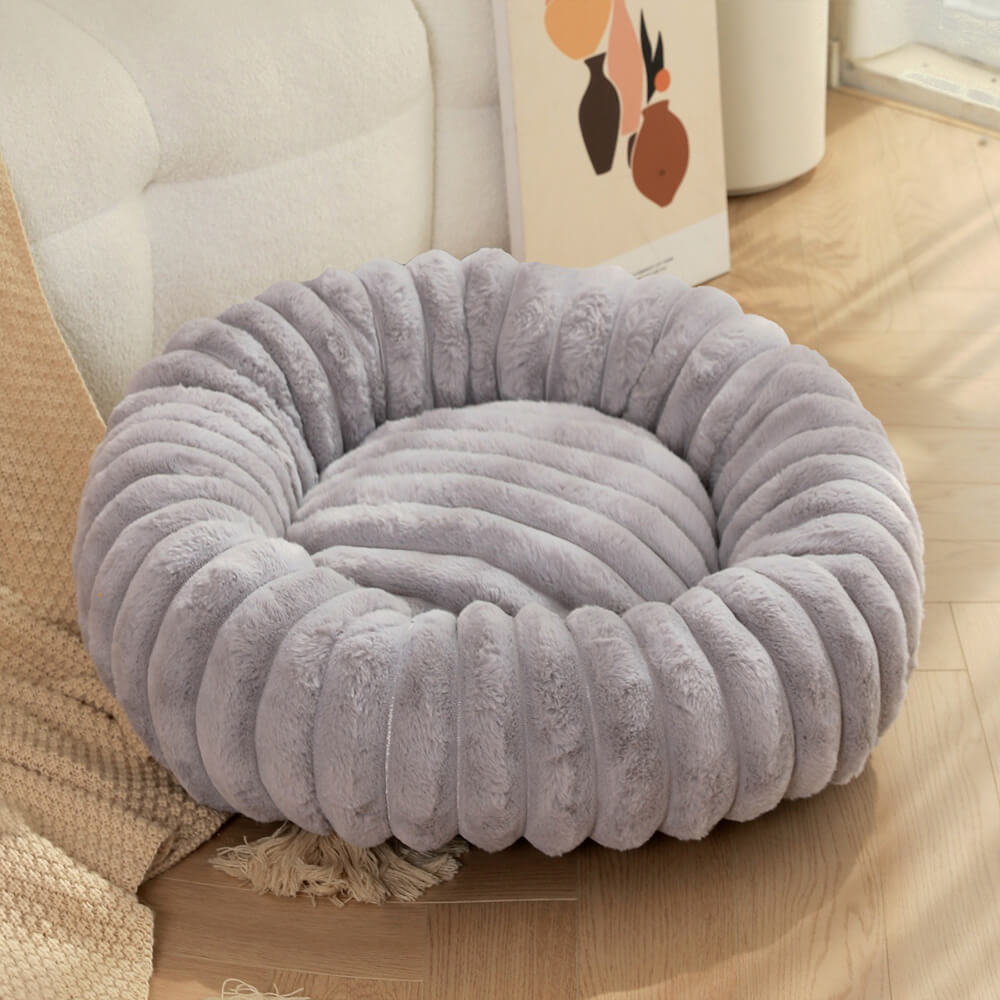Two cats napping together in a large plush round donut pet bed, very soft and calming.