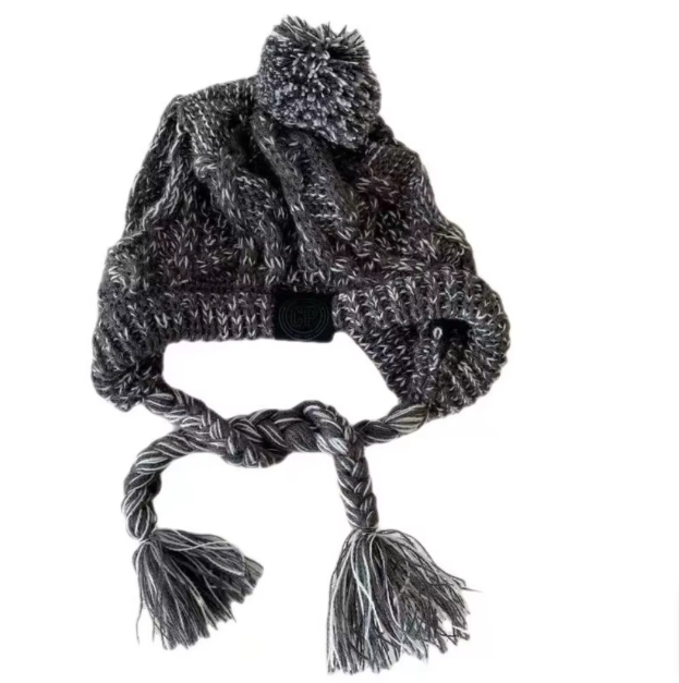 Happy small dog wearing a striped knit winter hat with a pom-pom, a stylish dog accessory.