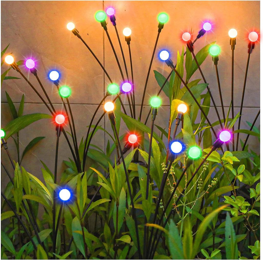 Night view of a garden with solar firefly lights glowing, enhancing the patio and lawn with starbursts.