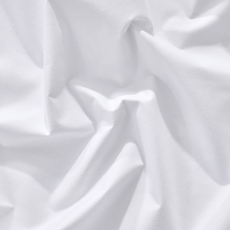 Corner of a bed with a fitted sheet, demonstrating its snug fit and waterproof mattress protection.