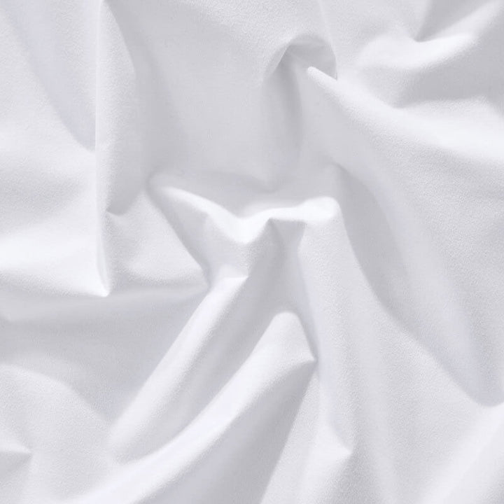 Corner of a bed with a fitted sheet, demonstrating its snug fit and waterproof mattress protection.