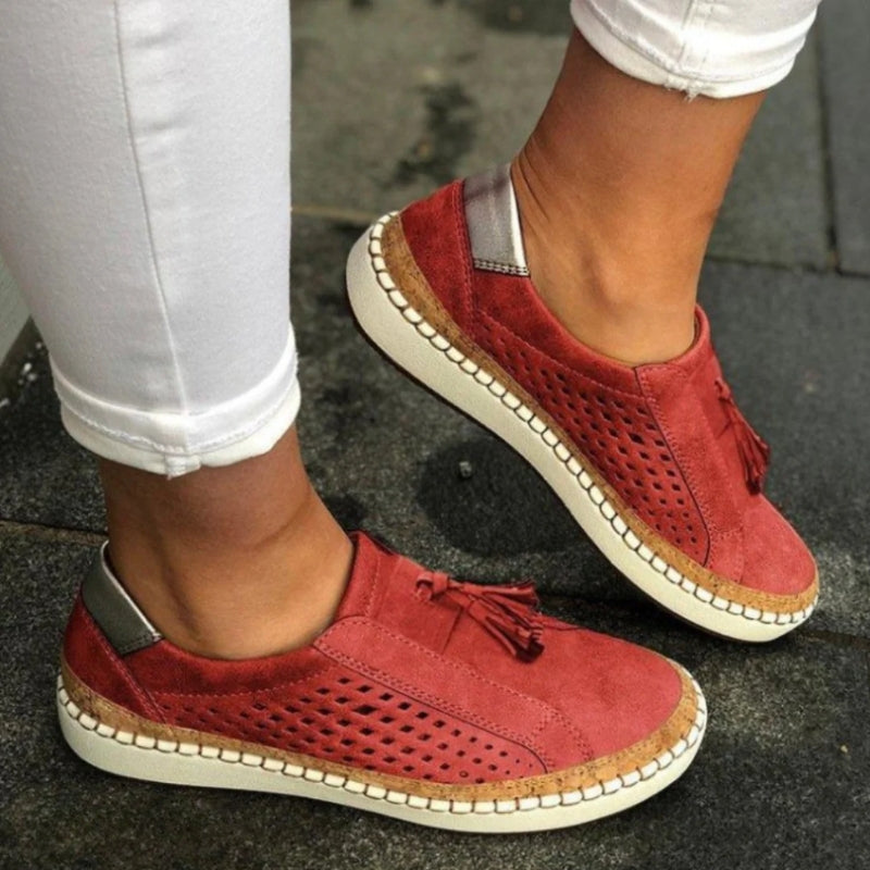 Women's breathable slip-on flats with arch support, tassel detail & perforated design for summer comfort.